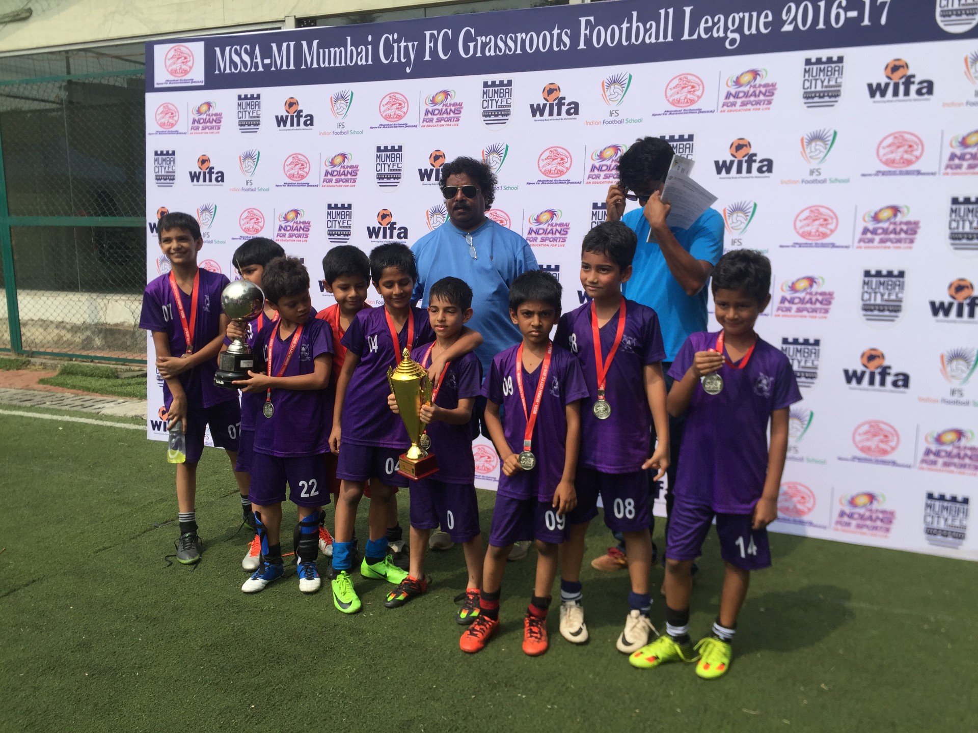 Youth team in purple kits with trophies and medals at the Mumbai City FC Grassroots Football League