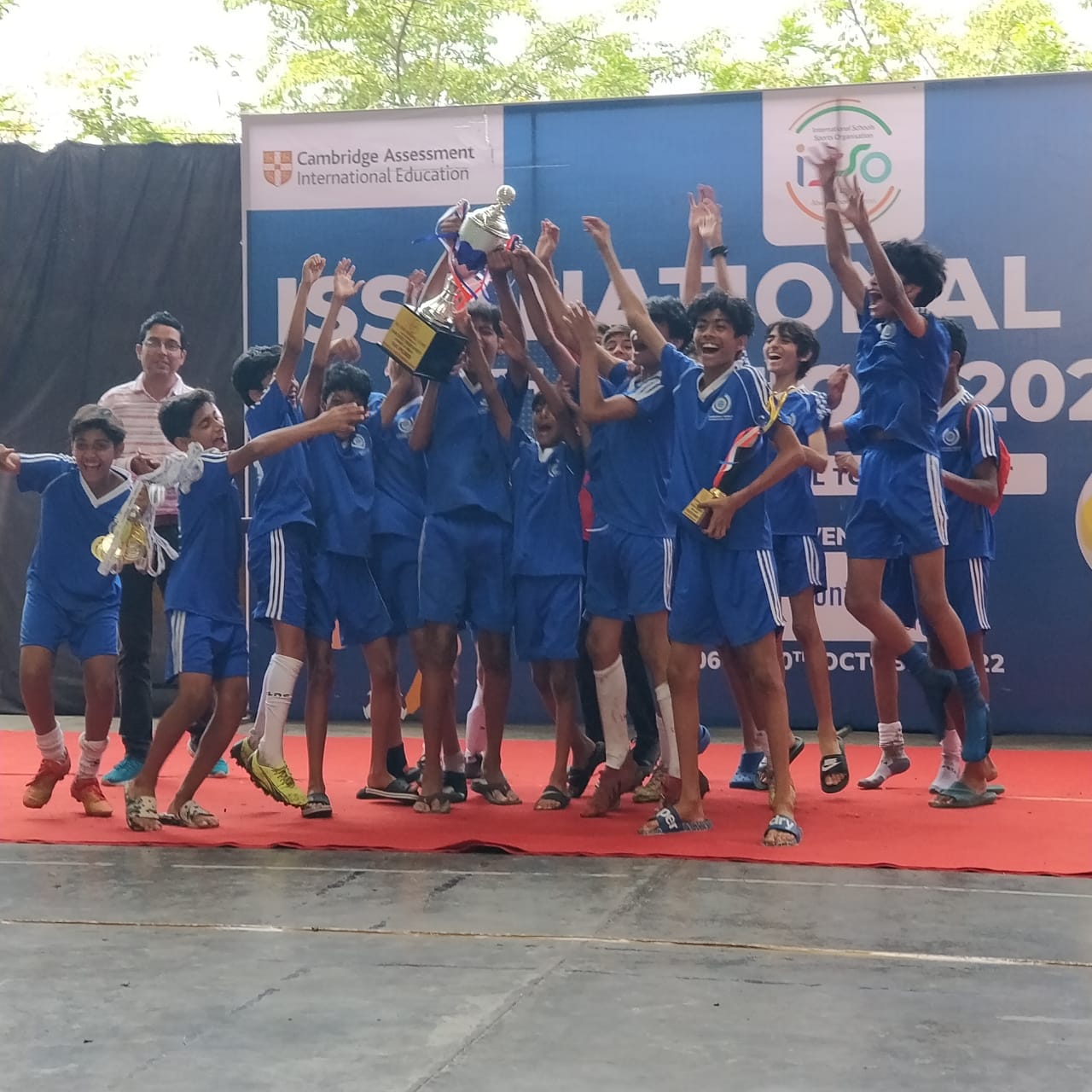 Team in blue kits cheering and lifting a trophy at the tournament award ceremony